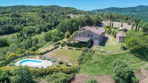 Une villa avec piscine, entourée d’une végétation luxuriante et de collines.