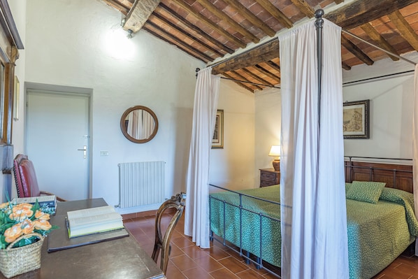 A room with a bed, a table with a book, a chair, a lamp, and a radiator. - Woodland Cottage (A3) with pool - Le Caldanelle (Civitello Paganico, Grosseto)