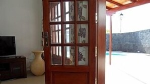 Een houten deur met glaspanelen, een televisie en een vaas op de vloer.