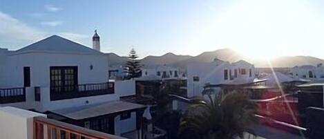 Un pueblo costero con edificios blancos, cielo despejado y un atardecer.