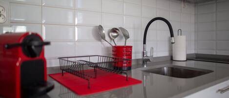 A kitchen with a red appliance, a sink, and a utensil holder.