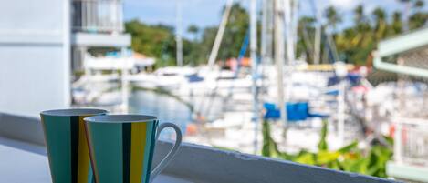 Deux tasses posées sur un rebord de fenêtre, avec vue sur le port de plaisance.
