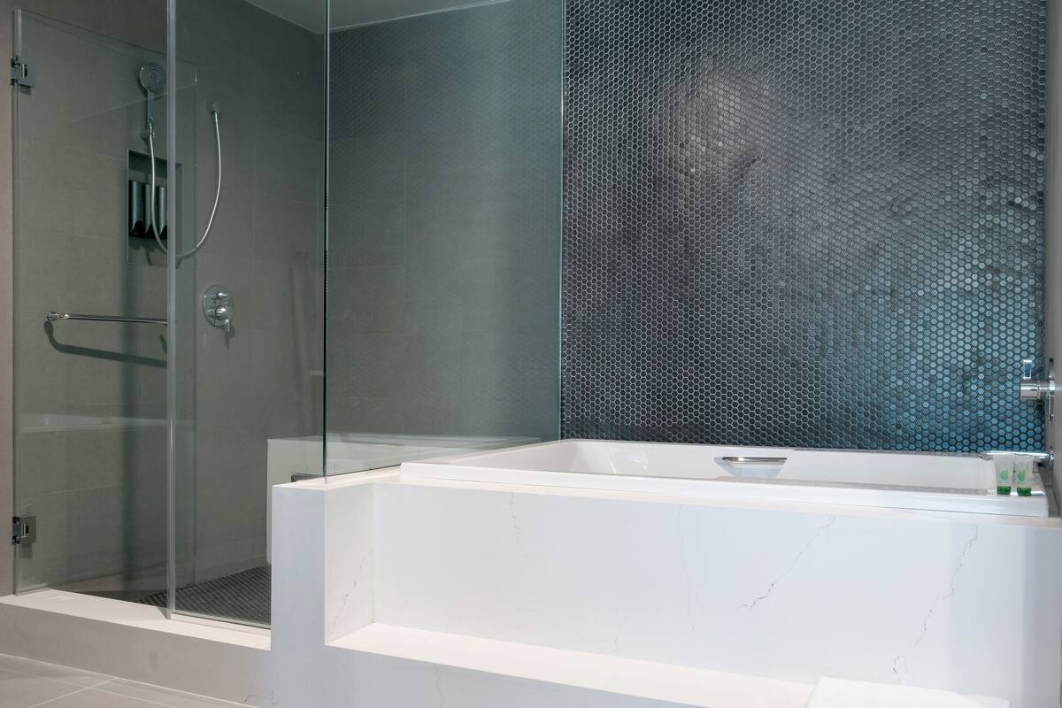 Une salle de bain moderne avec une douche à parois de verre, une grande baignoire et un mur à texture.