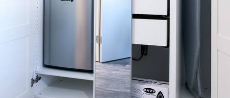 Un mueble de almacenamiento compacto y blanco con refrigerador y congelador integrados, con un diseño minimalista y superficie plana para colocar objetos.