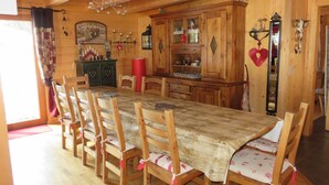 A wooden dining room with a large table and chairs, a cabinet with glass doors, and a mirror. - Large, sunny, peaceful chalet in the heart of nature in Les Diablerets, Switzerland. (Les Diablerets)