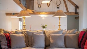 Ein gemütliches Wohnzimmer mit einer Eckcouch, zwei Lampen und Wanddekoration mit Geweihen.