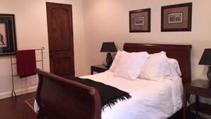 A bedroom with a wooden bed, two bedside tables with lamps, a red towel on a rack, and two framed pictures on the wall. - Room 4 Two in Montecito/ Santa Barbara (Montecito)