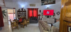 A living room with a television, a bookshelf, a dining area with chairs, and a sofa. - Saly: House / Villa - Saly (Saly)