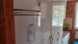 A kitchen with white cabinets, a refrigerator, and a blue trash bin. - Saly: House / Villa - Saly (Saly)