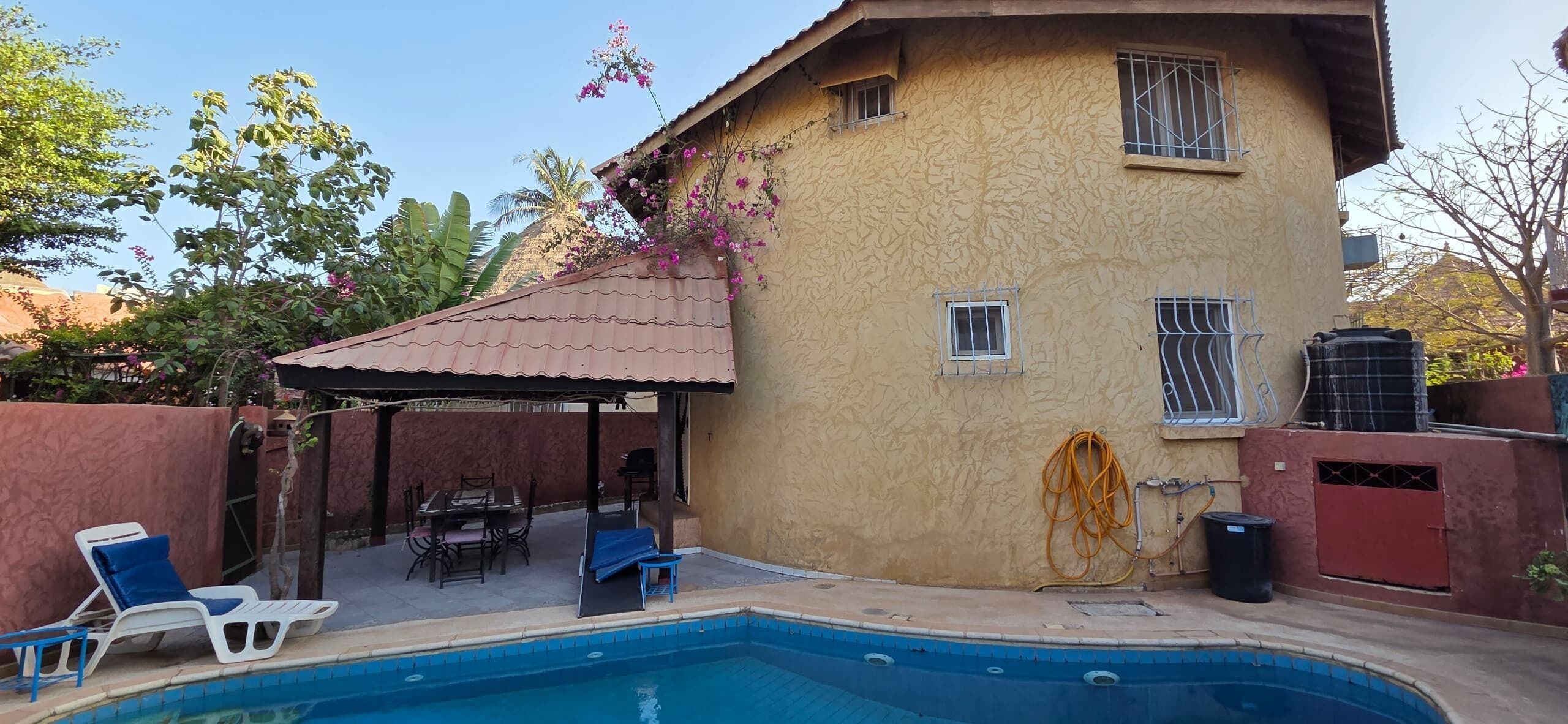 A residential property with a swimming pool, outdoor furniture, and a covered patio area.