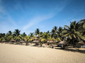 A beach with palm trees and thatched-roof structures. - Saly: House / Villa - Saly (Saly)