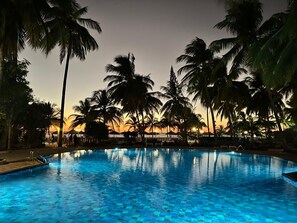 A swimming pool surrounded by palm trees at dusk. - Saly: House / Villa - Saly (Saly)