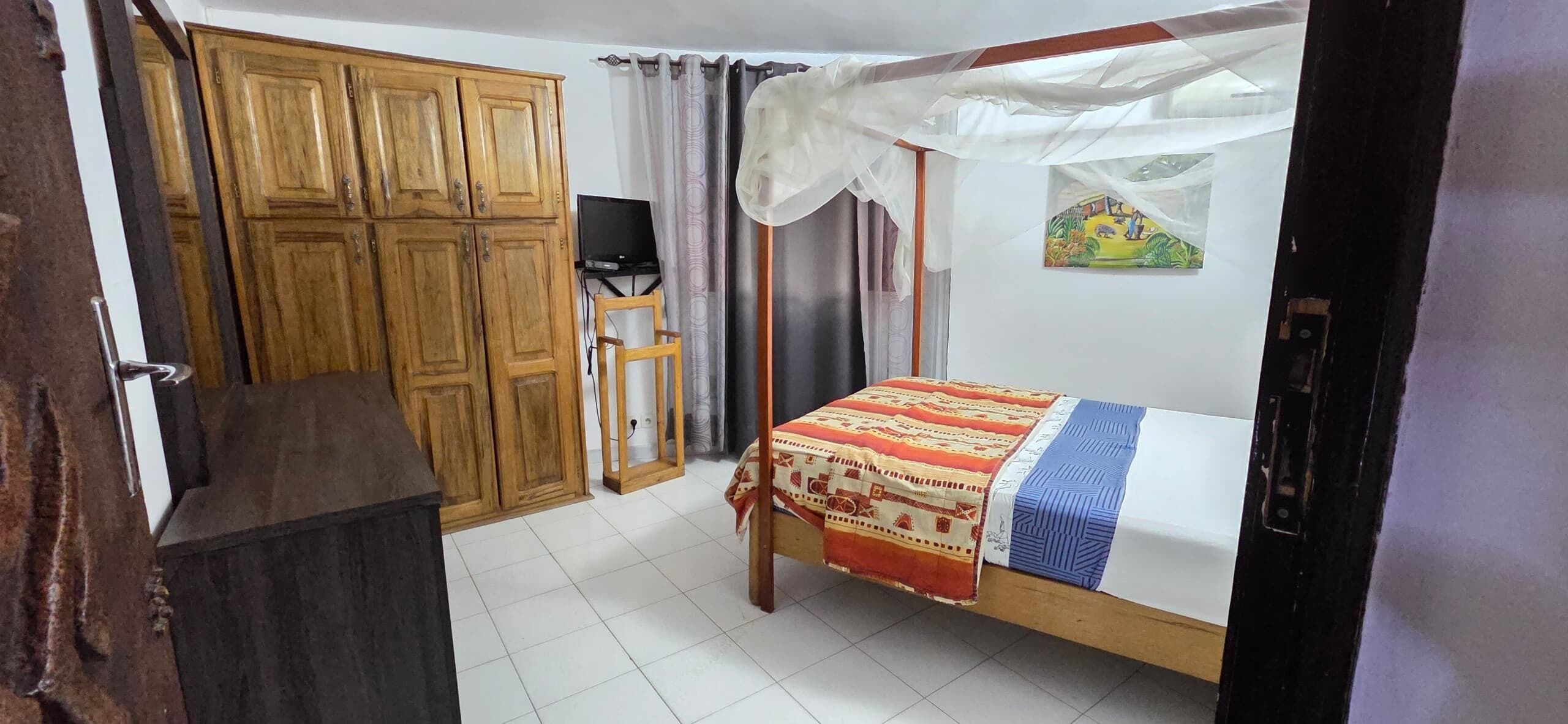 Une chambre à coucher avec un lit, une armoire en bois et un téléviseur.