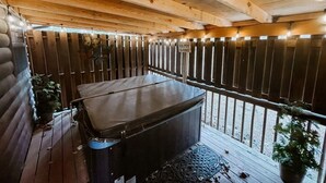 Eine Holzterrasse mit Whirlpool, Holzzaun und Kübelpflanzen.