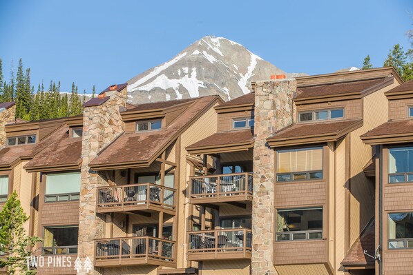 Un hotel de varios pisos con balcones y montañas al fondo.