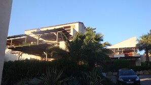 A building with a flat roof, a covered outdoor area, and a parked car.