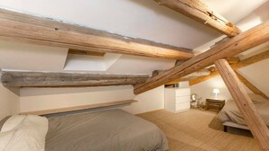 A bedroom with a loft-style ceiling, a bed, a nightstand, and a dresser. - Nice new 2 bedroom town center apartment (Avignon)