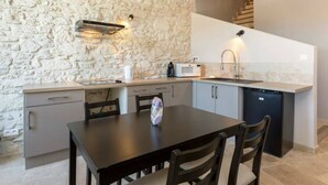 A compact kitchen with a stone wall, a microwave, a sink, and a dishwasher. - Nice new 2 bedroom town center apartment (Avignon)