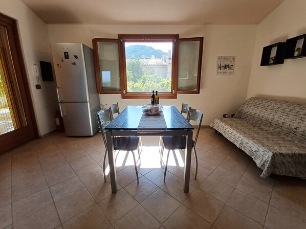 Una cocina compacta con mesa de comedor, sillas, refrigerador y sofá.