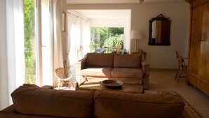 Un salon avec un canapé, un fauteuil, une table sur laquelle se trouve un saladier, une lampe et un miroir accroché au mur.
