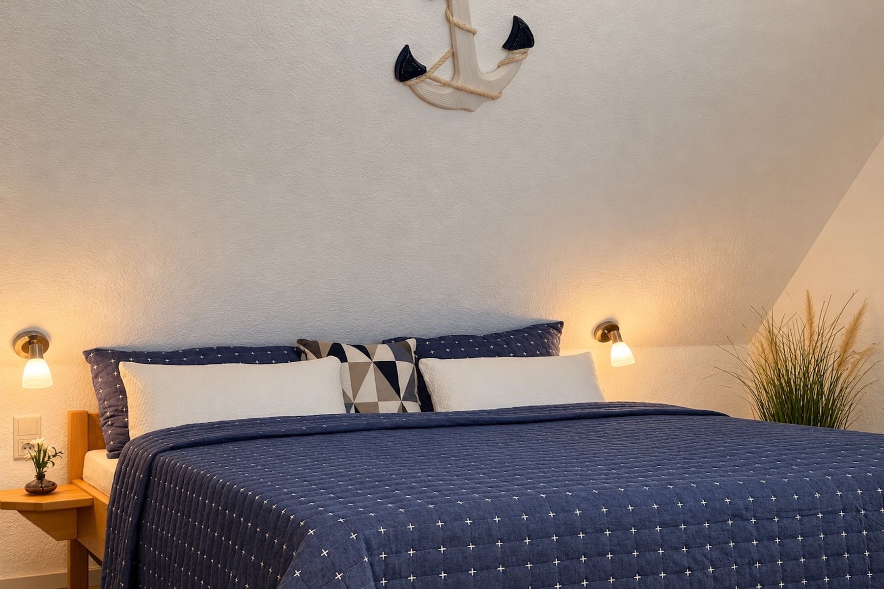 A bedroom with a bed, nightstands, a wall-mounted light fixture, and a plant.