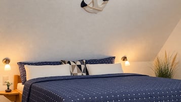 A bedroom with a bed, nightstands, a wall-mounted light fixture, and a plant.
