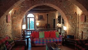 Una habitación acogedora con un sofá a cuadros, mesas de madera y un arco de piedra.