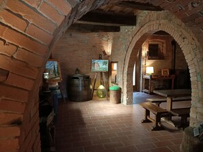 Un interior rústico con paredes de ladrillo, un banco de madera, una mesa y un cuadro en la pared.