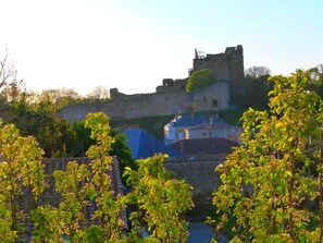 Une structure ressemblant à un château, avec un mur de pierre et un bâtiment doté d’un toit bleu, visible au premier plan.