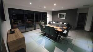 Un espace repas moderne avec une cloison en verre, une table en bois et des chaises noires.