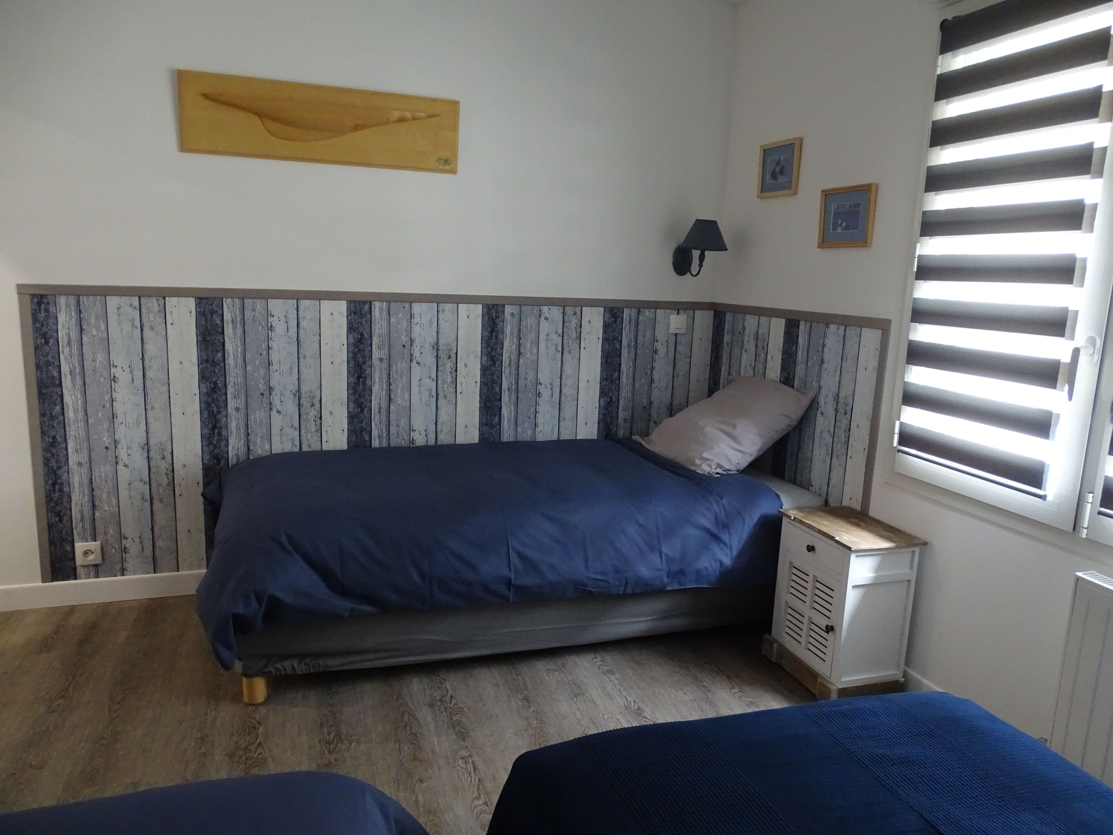 Una camera da letto con un letto, un comodino, una lampada e una finestra con persiane.