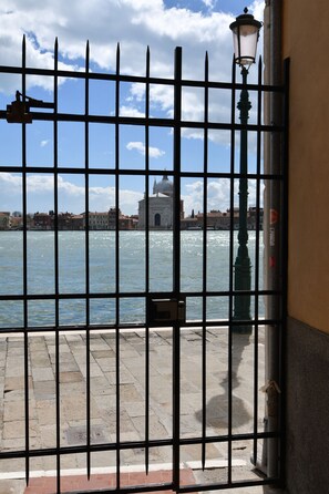 Blick durch ein Metallgitter, mit einer Straßenlaterne und einem Gebäude im Hintergrund.
