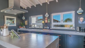 Une cuisine moderne dotée d’un grand îlot central, d’appareils électroménagers intégrés et de luminaires suspendus.