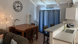 A compact living space with a dining area, kitchenette, and a large clock on the wall. - Fun at the Beach !!!!!! (Oxnard)