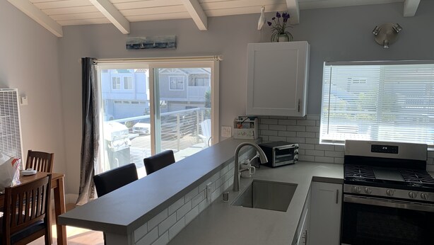 A modern kitchen with a central island, a built-in oven, and a window with blinds. - Fun at the Beach !!!!!! (Oxnard)