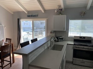A modern kitchen with a central island, a built-in oven, and a window with blinds. - Fun at the Beach !!!!!! (Oxnard)