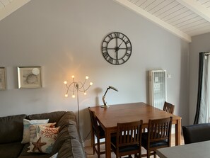 A dining area with a wooden table and chairs, a wall clock, and a ceiling fan. - Fun at the Beach !!!!!! (Oxnard)