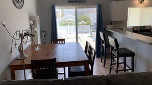 A dining area with a wooden table and chairs, a ceiling fan, and a view of the outside balcony. - Fun at the Beach !!!!!! (Oxnard)