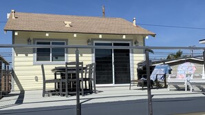 A two-story house with a flat roof, a large sliding glass door, and a balcony with metal railings. - Fun at the Beach !!!!!! (Oxnard)