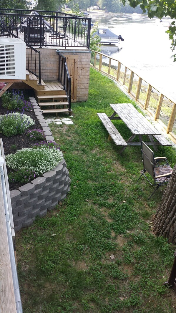 Un patio trasero con una terraza de madera, una jardinera de piedra y una mesa de picnic.