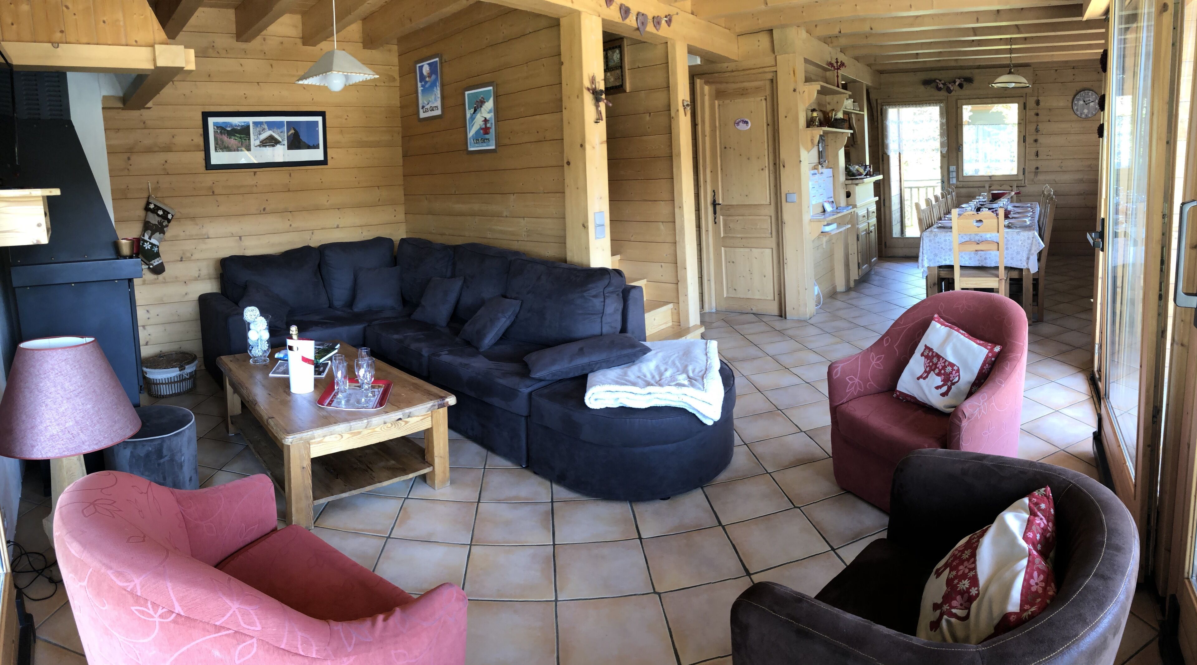 Een knusse woonkamer met een donkerblauwe modulaire bank, een houten salontafel en twee fauteuils.
