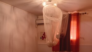 Ein Zimmer mit zwei Betten, einem Deckenventilator und einem kleinen Tisch.