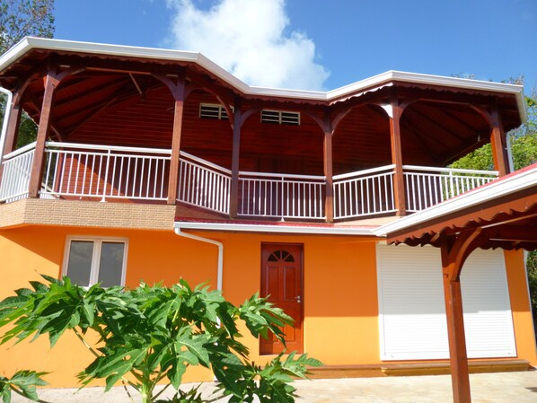 Une maison à deux étages avec un balcon, un garage et un jardin.
