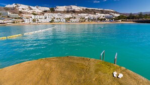 A coastal hotel with a pool, beach, and hillside views. - Viuter - Marina Vista Puerto Rico (Mogán)