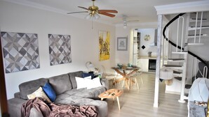 A modern living room with a grey sofa, a wooden coffee table, and a staircase leading to a second floor. - Viuter - Marina Vista Puerto Rico (Mogán)