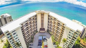 A high-rise hotel with a central courtyard parking area, surrounded by palm trees and ocean views. - Royal Kahana 318 Studio Bedroom Condo by RedAwning (Lahaina)