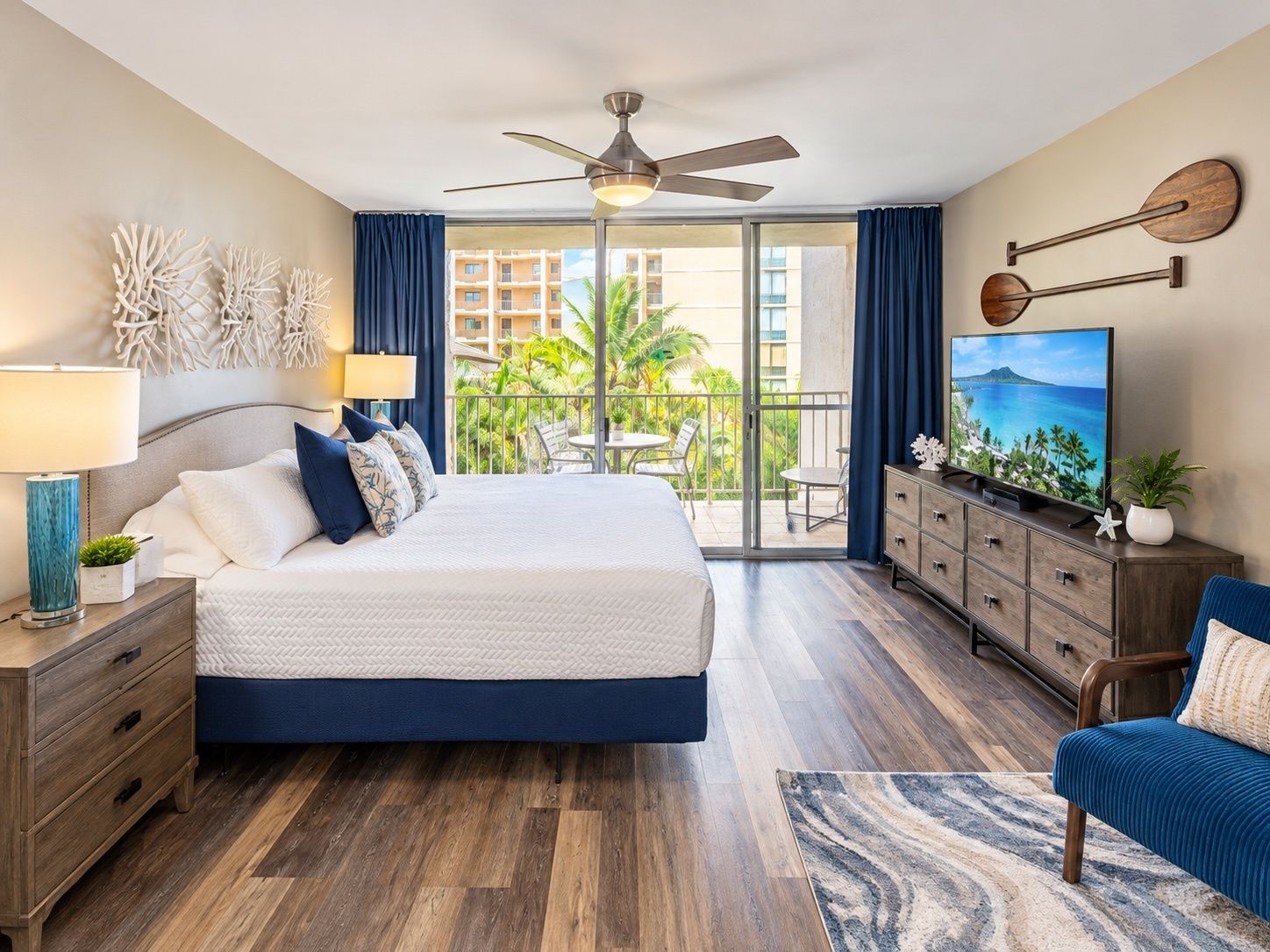 Ein Hotelzimmer mit Bett, Fernseher, Balkon und Blick sowie Deckenventilator.