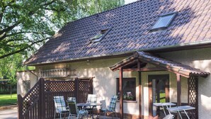 Een huis met een overdekte patio, zitplaatsen buiten en een gazon.