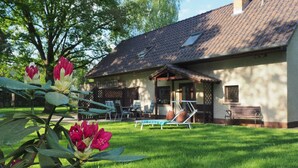 Een huis met een pannendak, een overdekte veranda en een gazon met buitenmeubilair.