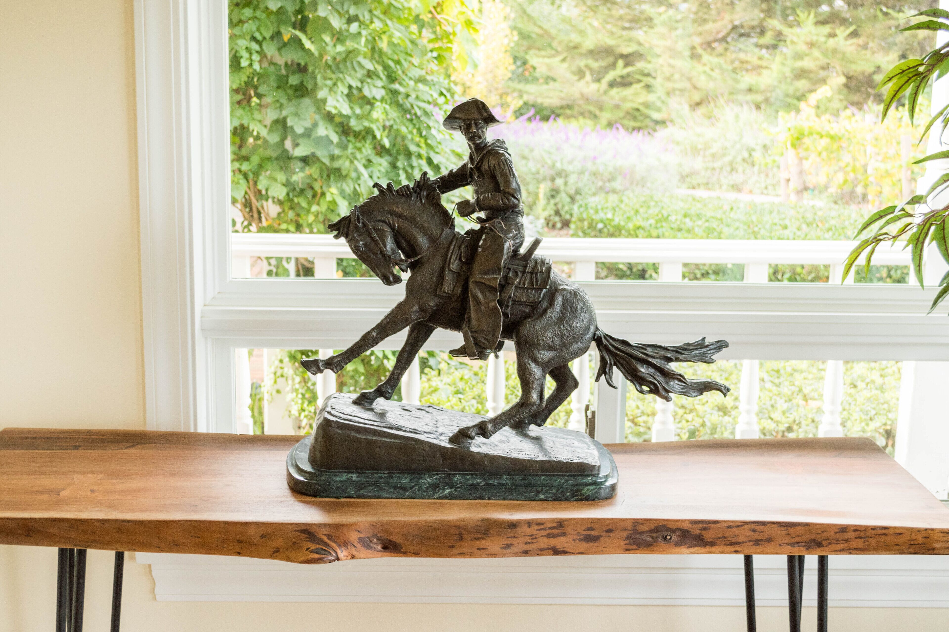 A statue of a man on a horse on a wooden table.